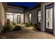 A ground-level view shows the paved courtyard, decorative plants, and the facade of the house with its entrance door at 18016 E Wolf Tree Ln, Rio Verde, AZ 85263