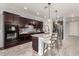 Modern kitchen with dark wood cabinets, granite countertops, a large kitchen island, and stainless steel appliances at 18146 W Tina Ln, Surprise, AZ 85387