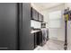 Modern laundry room boasts built-in cabinets, tile flooring, and a front-load washer and dryer at 18146 W Tina Ln, Surprise, AZ 85387