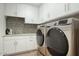 Well-equipped laundry room with modern washer and dryer, ample cabinet space, and stylish backsplash at 18720 N 101St St # 3021, Scottsdale, AZ 85255