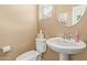 This half bathroom features a pedestal sink, neutral paint, and a round mirror at 2013 N 77Th Gln, Phoenix, AZ 85035