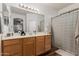 Bathroom vanity with wood cabinets, neutral countertops, and black and white shower curtain at 20916 E Desert Hills Blvd, Queen Creek, AZ 85142