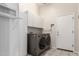 Functional laundry room featuring washer, dryer, storage cabinets, and a hanging rack at 2450 E Glass Ln, Phoenix, AZ 85042