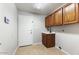 Laundry room with upper wood cabinets, tiled floor, sink, and door to exterior at 2923 N 63Rd St, Mesa, AZ 85215