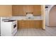 A view of the kitchen area showing light oak cabinets, tile floors and white appliances at 2928 W Cactus Rd, Phoenix, AZ 85029