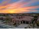 Stunning sunset view of a luxury home featuring a three-car garage and desert landscaping at 32754 N 15Th Gln, Phoenix, AZ 85085