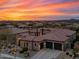 Stunning home boasts a tile roof, stone accents, three-car garage, and meticulously landscaped grounds under a breathtaking sunset at 32754 N 15Th Gln, Phoenix, AZ 85085