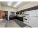 A bright kitchen with black cabinets, a white oven and refrigerator, and a sink beneath a window at 3330 E Main St # 7, Mesa, AZ 85213