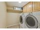 Functional laundry area with washer, dryer, overhead cabinets and shelving at 3336 E Linda Ct, Gilbert, AZ 85234