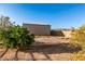 Backyard view of a metal barn structure behind desert landscaping and a block fence at sunset at 38301 N 15Th Ave, Phoenix, AZ 85086