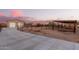 Outdoor equestrian facility with a covered pen, metal fencing, a barn, and a concrete driveway at sunset at 38301 N 15Th Ave, Phoenix, AZ 85086