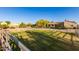 Grassy horse paddock features secure metal fencing, with mature trees and a residence in the background at 38301 N 15Th Ave, Phoenix, AZ 85086