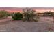 A horse arena showcases gravel ground, vegetation, and partial fencing with shelters and the residence in the background at 38301 N 15Th Ave, Phoenix, AZ 85086