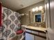 Well-lit bathroom with a decorative mirror, modern vanity, and patterned shower curtain at 4546 N 84Th Ln, Phoenix, AZ 85037