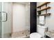 Modern bathroom shower featuring decorative tile, a glass door, and stylish wood shelving for storage at 725 E Country Gables Dr, Phoenix, AZ 85022