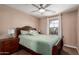 Cozy bedroom showcasing a wood-framed bed, nightstand, fan, and window bringing in natural light at 7252 N 90Th Ln, Glendale, AZ 85305