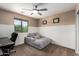 Bedroom featuring a window, desk, comfortable seating, wainscotting, a ceiling fan, and neutral walls at 7252 N 90Th Ln, Glendale, AZ 85305