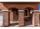 Covered front porch with brick columns, decorative iron door, and a seating area with a small table at 7252 N 90Th Ln, Glendale, AZ 85305