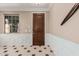 Elegant foyer with a dark wood door, decorative wall trim, and black and white checkered tile flooring at 7252 N 90Th Ln, Glendale, AZ 85305