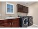 Well-lit laundry room featuring a large sink and modern, front-loading washer and dryer units at 7252 N 90Th Ln, Glendale, AZ 85305