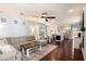 Bright, open-concept living room with dark wood floors, modern furnishings, ceiling fan and seamless flow to kitchen at 7428 W Montgomery Rd, Peoria, AZ 85383