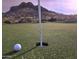 Close-up of a golf green with a ball near the hole and a mountain backdrop, highlighting the course's beauty at 8965 E Red Mountain Ln, Gold Canyon, AZ 85118