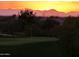 Scenic golf course view at sunset, showcasing mountain silhouettes and lush greenery at 8965 E Red Mountain Ln, Gold Canyon, AZ 85118