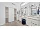 Well-lit bathroom featuring dual vanity sinks, marble countertops, modern lighting, and a walk-in closet at 9138 E Emerald Dr, Sun Lakes, AZ 85248