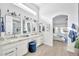 Bright bathroom with dual vanity sinks, marble countertops, modern lighting, and an arched doorway to the bedroom at 9138 E Emerald Dr, Sun Lakes, AZ 85248