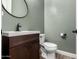 Stylish powder room featuring a wood vanity, circular mirror, and coordinating gray walls at 9302 W White Feather Ln, Peoria, AZ 85383