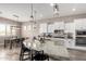 Open kitchen layout features island seating, white cabinetry, stainless appliances, and modern lighting at 9302 W White Feather Ln, Peoria, AZ 85383