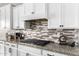 Kitchen with granite countertops, white cabinetry, stainless steel appliances, and stylish backsplash at 9302 W White Feather Ln, Peoria, AZ 85383