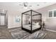 Spacious main bedroom showcasing a stylish four-poster bed, neutral tones, and natural light at 9302 W White Feather Ln, Peoria, AZ 85383