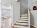 Bright staircase features wood-look stairs, white risers, and decor at top landing with view into adjacent living space at 9574 W Quail Ave, Peoria, AZ 85382