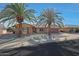 Home exterior featuring lush landscaping, mature palms, and a well-maintained facade with a two-car garage at 10307 W Desert Rock Dr, Sun City, AZ 85351