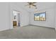 A spacious carpeted bedroom features neutral colored walls, a ceiling fan, and an ensuite bathroom at 15853 S 17Th Dr, Phoenix, AZ 85045