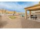 Spacious backyard with a covered patio, barbecue area, and gravel landscaping at 17176 W Molly Ln, Surprise, AZ 85387