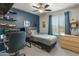 Stylish bedroom featuring navy blue wall, toys on shelves, gray bedspread, and natural light at 17176 W Molly Ln, Surprise, AZ 85387