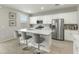Bright kitchen boasts a large center island with seating, stainless steel appliances, and sleek white cabinetry at 17176 W Molly Ln, Surprise, AZ 85387