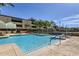 Large swimming pool with lounge chairs and a seating area, surrounded by trees at 207 W Clarendon Ave # G18, Phoenix, AZ 85013
