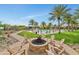 Inviting outdoor fire pit area with Adirondack chairs, surrounded by a lush landscape and palm trees at 20718 W Colter St, Buckeye, AZ 85396