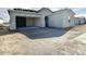 A house with gray unfinished siding stands in the neighborhood with an unfinished driveway and garage at 22693 E Saddle Way, Queen Creek, AZ 85142