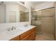 Bathroom featuring dual sinks, quartz countertops, and tiled shower with glass doors at 2560 E Indian Wells Pl, Chandler, AZ 85249