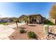 Shot of a one-story house featuring desert landscaping, palm trees, and a wide driveway leading to a two-car garage at 33224 N Cat Hills Ave, San Tan Valley, AZ 85144