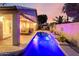 Inviting outdoor pool with waterfall feature and a covered patio seating area at twilight at 3720 N 150Th Ct, Goodyear, AZ 85395