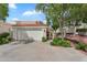 Charming home featuring a two-car garage, driveway, and desert landscaping, all set against a backdrop of blue sky and mature trees at 4225 N 21St St # 22, Phoenix, AZ 85016