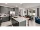This kitchen features stainless appliances, gray cabinets, white countertops and an island with seating facing the dining area at 5383 N 205Th Dr, Buckeye, AZ 85396
