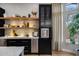Modern kitchen features custom shelving, sleek black cabinets, a stainless steel refrigerator, and a built-in water dispenser at 5829 W Alyssa Ln, Phoenix, AZ 85083