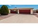 Charming home featuring a large driveway, low-maintenance desert landscaping and a red garage door at 6305 E Adobe Rd, Mesa, AZ 85205