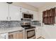 Modern kitchen featuring white cabinets, tile backsplash, and stainless appliances at 6305 E Adobe Rd, Mesa, AZ 85205